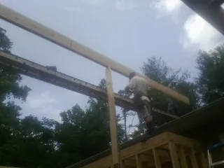 Carpenter setting a ridge beam over a new addition frame — Ice Dam Removal by Roofing Brothers in Solomon