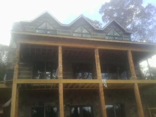 Dormers and porch framing on a large log home under construction — Roof Coating work by our crew in Solomon