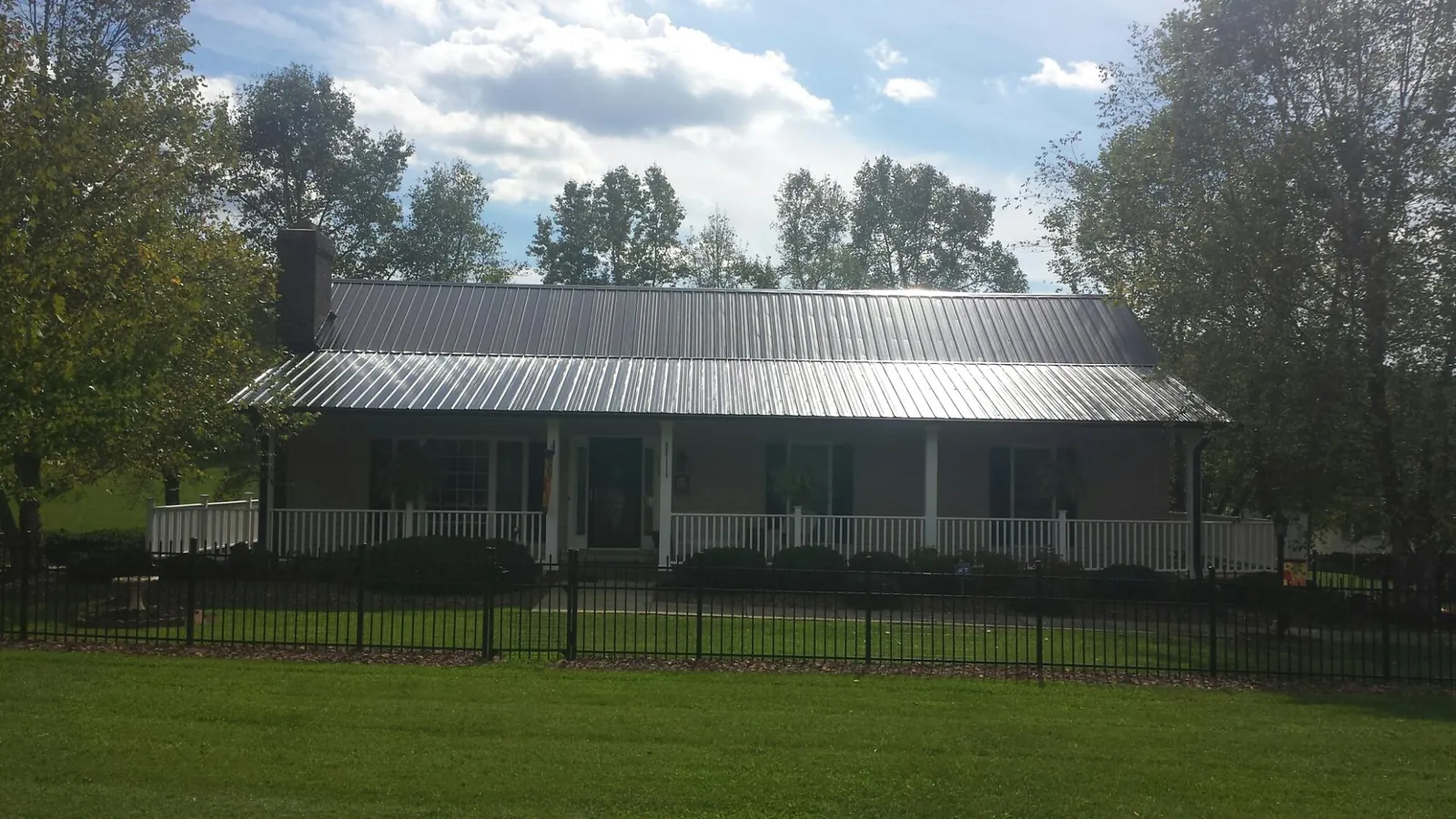 Gray metal roof on a brick ranch with a full width front porch — Gutter Guard Installation work by our crew in Solomon