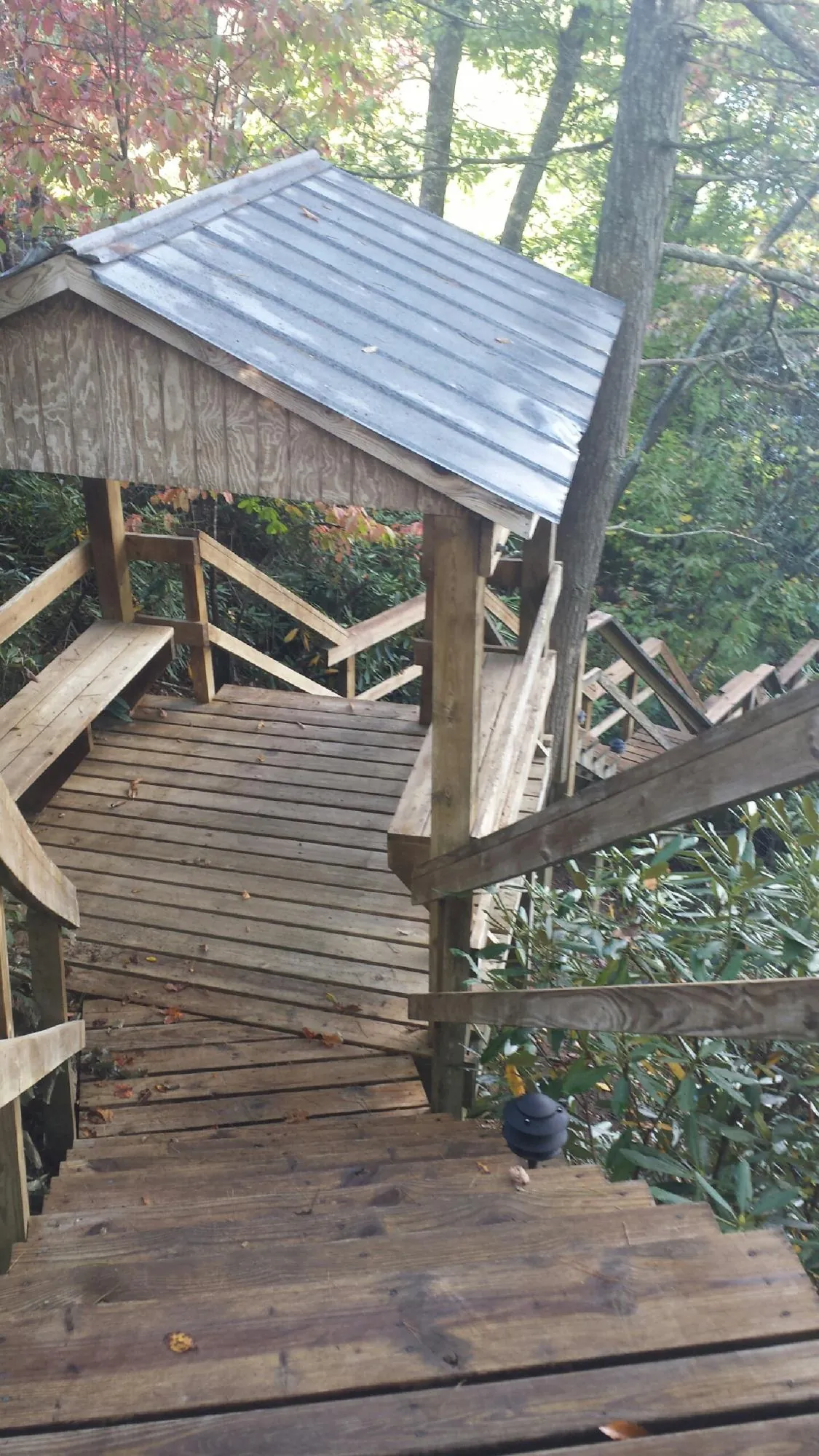 Metal roofed shelter over wooden steps on a wooded walkway — Skylight Repair & Installation work by our crew in Solomon