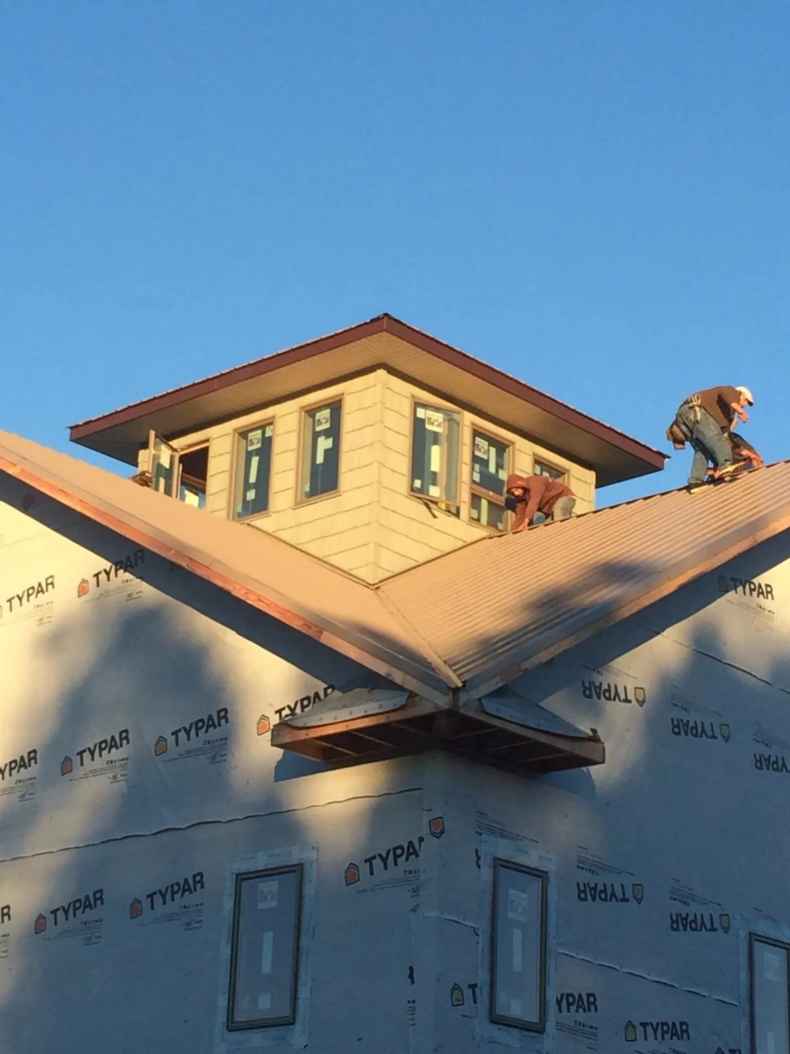 Roofers working around a rooftop cupola on a new metal roof at sunset — Roof Waterproofing in Solomon by Roofing Brothers